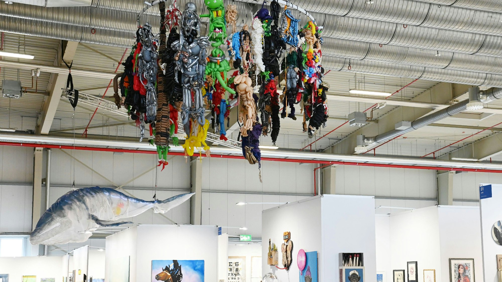 Die zwei größten Werke der Discovery Art Fair hängen von der Decke: Horrorfiguren aus Ballons, denen die Luft ausgeht und ein lebensgroßer Plastikwal. Foto von Alexander Schwaiger.