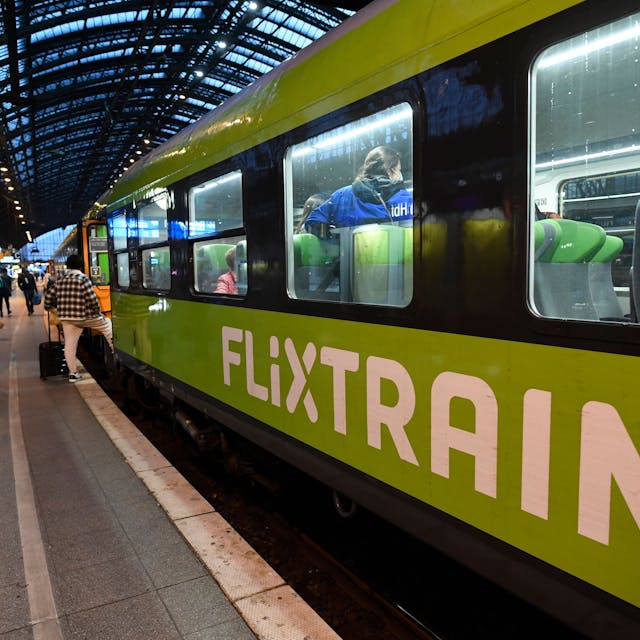 Mehrere Reisende steigen in einen Flixtrain am Kölner Hauptbahnhof, der Zug ist markant grün lackiert. Im Innenraum sind mehrere Fahrgäste zu sehen.