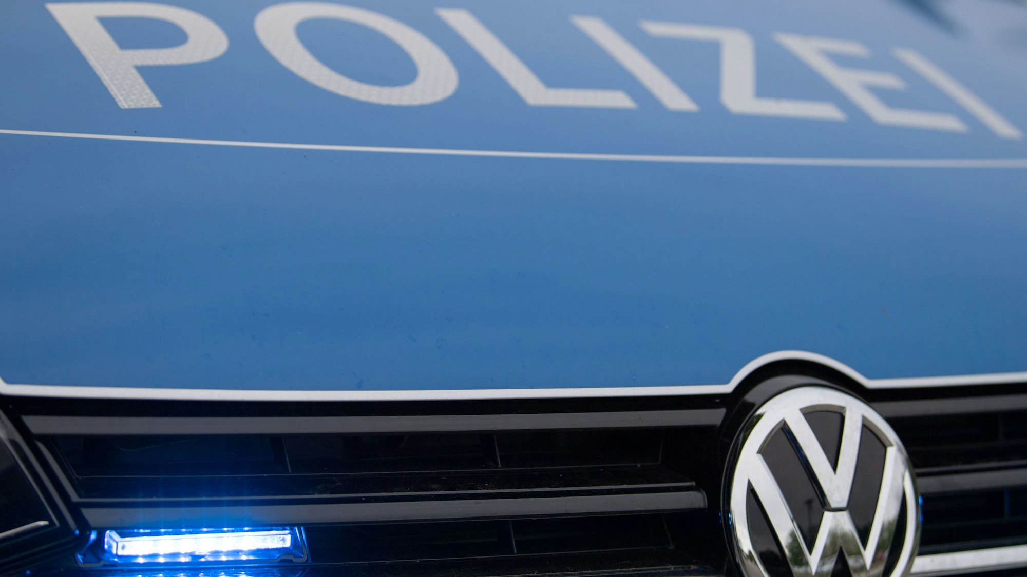 Ein Blaulicht leuchtet im Kühlergrill eines Polizeiautos.