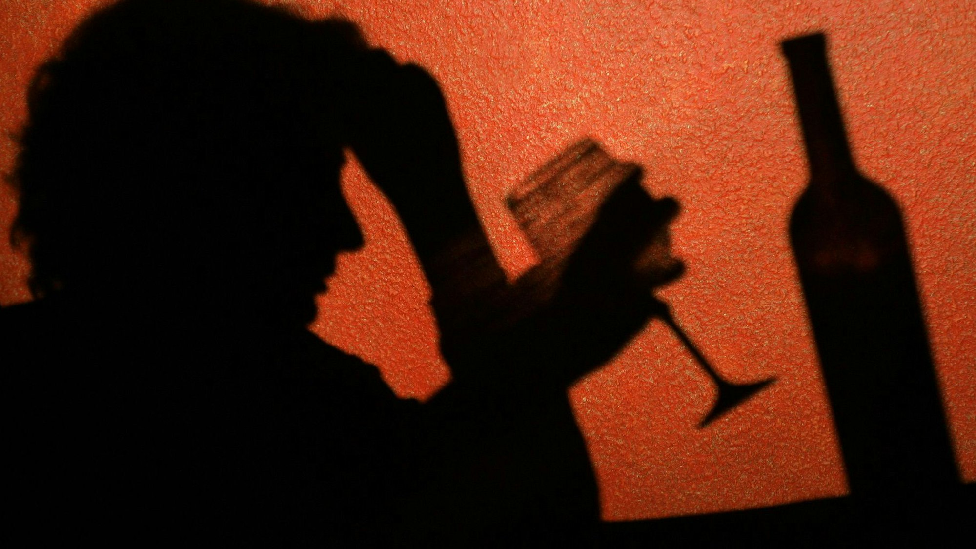 Der Schatten einer Frau, die ein Glas Wein trinkt, ist an der Wand in einer Kneipe in Frankfurt (Oder) zu erkennen.  Laut einer aktuellen Studie sterben Alkoholabhängige deutlich früher.