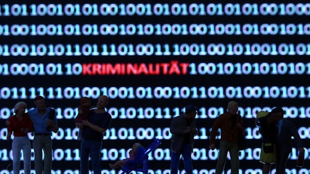 Modellfiguren stehen vor einem Computerbildschirm mit Zeichen des Binärcodes und dem Schriftzug "Kriminalität"