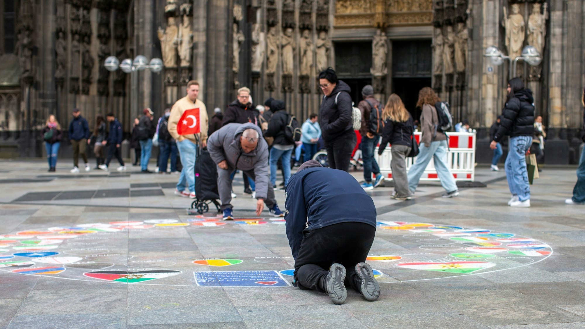 Ein Flaggenmaler vor dem Kölner Dom.