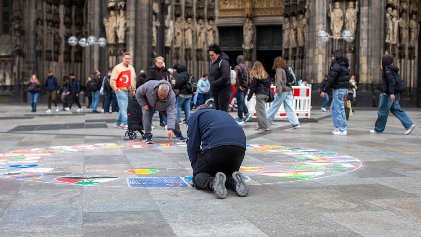 Ein Flaggenmaler vor dem Kölner Dom.