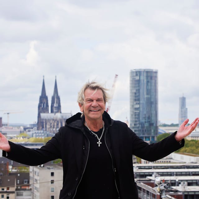 Matthias Reim auf dem Dach der Lanxess-Arena, er lacht und breitet die Arme aus.