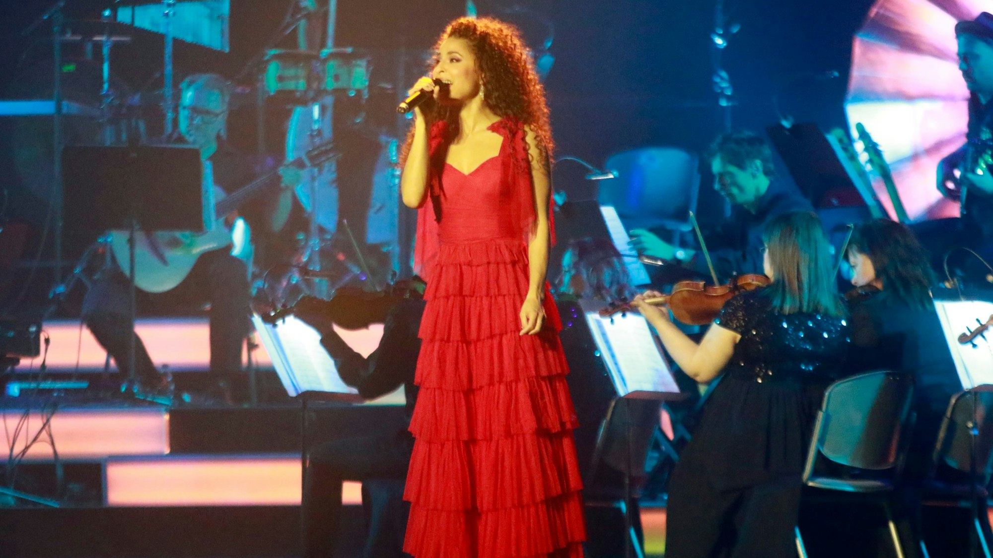 Patricia Meeden steht in einem roten Kleid auf der Bühne und singt.