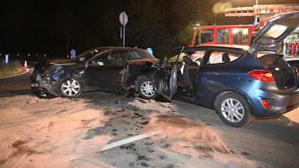 Zwei beschädigte Autos. Im Hintergrund ein Einsatzfahrzeug der Feuerwehr.