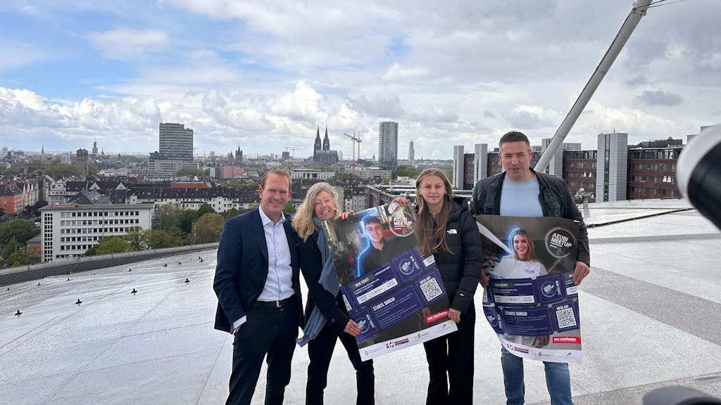 Zwei Männer und zwei Frauen auf dem Dach der Lanxess-Arena in Köln, sie zeigen Plakate.