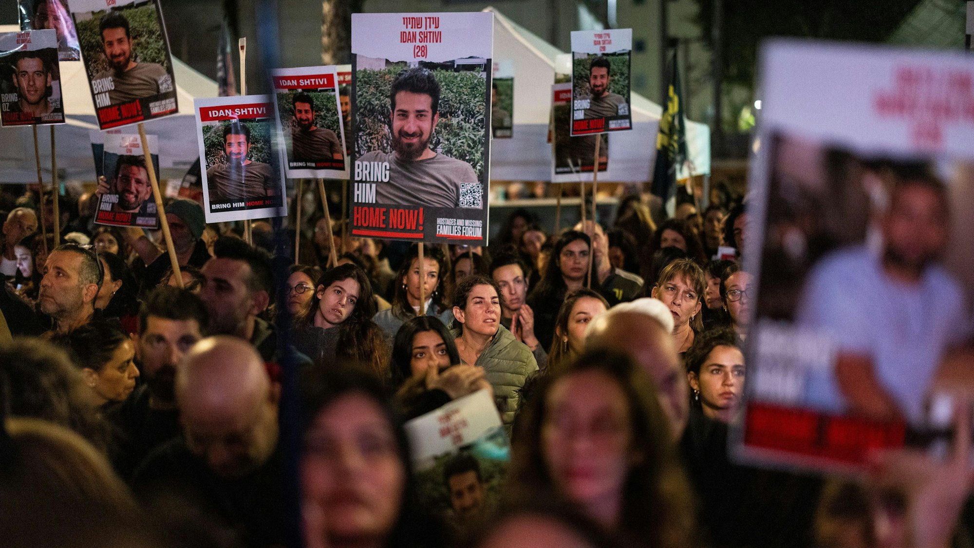 Eine Menschenmenge steht auf einer Straße und hält Plakate hoch, die einen Mann zeigen, bevor er als Geisel genommen wurde. (Archivbild)