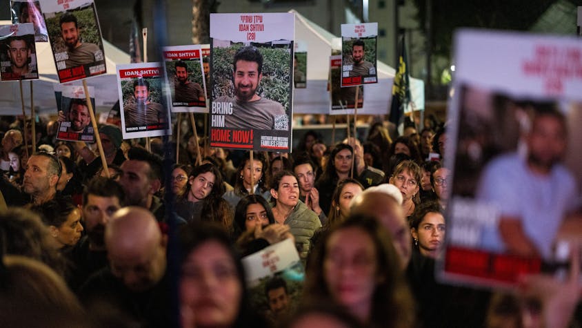Eine Menschenmenge steht auf einer Straße und hält Plakate hoch, die einen Mann zeigen, bevor er als Geisel genommen wurde. (Archivbild)