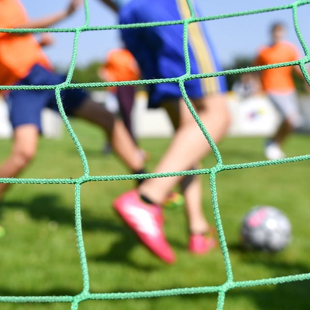 Fußballspielende Kinder durch ein Tornetz fotografiert&nbsp;