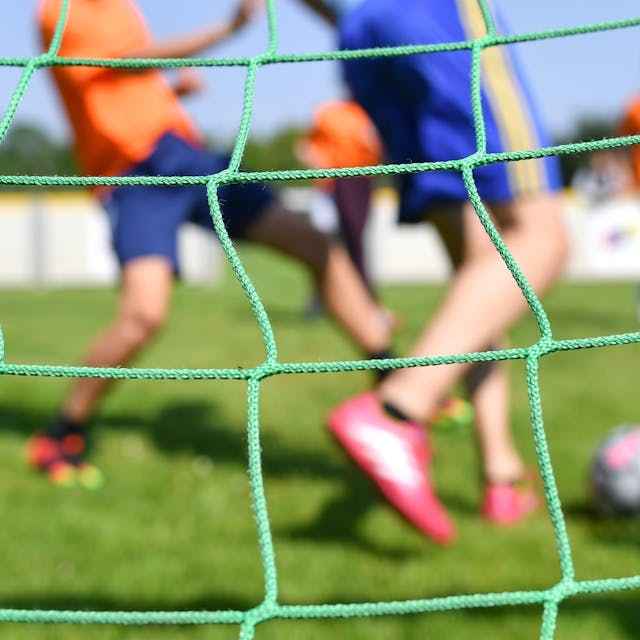 Fußballspielende Kinder durch ein Tornetz fotografiert&nbsp;