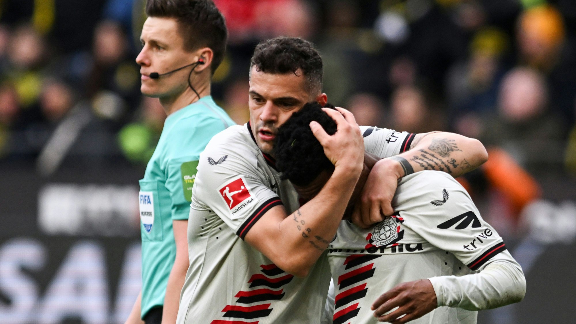 Leverkusens Granit Xhaka tröstet den verletzten Leverkusens Nathan Tella neben Schiedsrichter Daniel Siebert.