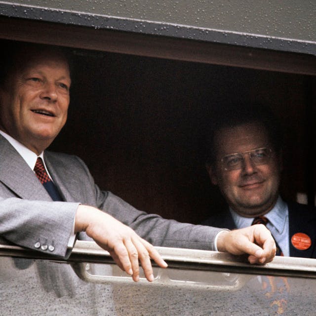Willy Brandt steht am geöffneten Fenster eines Zuges, auf dem Bild rechts steht sein Referent Günter Guillaume. Beide blicken aus dem Fenster.