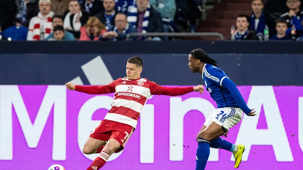 Fortuna Düsseldorfs Christos Tzolis flankt, Schalkes Brandon Soppy versucht zu blocken.