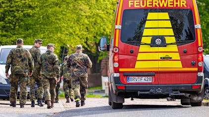 Soldaten der Bundeswehr gehen eine Straße in einem Wohngebiet entlang, vorbei an einem Einsatzfahrzeug der Feuerwehr. Trotz einer neuen Suchtaktik wird der sechs Jahre alte Arian aus Elm in Bremervörde weiter vermisst.