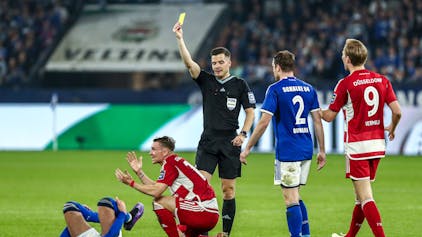 Fortuna Düsseldorfs Felix Klaus kniet am Boden, Schiedsrichter Harm Osmers zeigt ihm die Gelbe Karte.