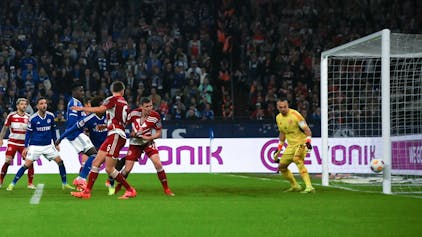 Fortuna Düsseldorf und Schalke 04 Spieler schauen auf den Ball, der den Pfosten vom Tor trifft.