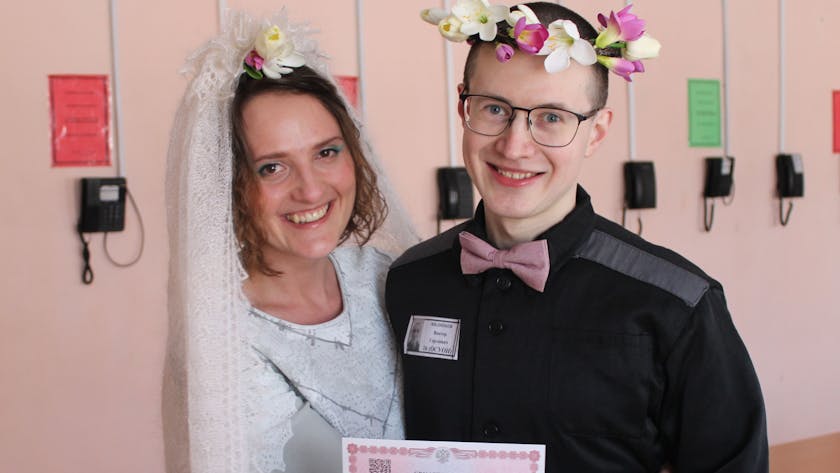 Evgenia Kulakova undViktor Filinkov, sie mit weißem Schleier, er mit Blumenkranz im Haar, bei der Hochzeit im Gefängnis. Beide lachen.
