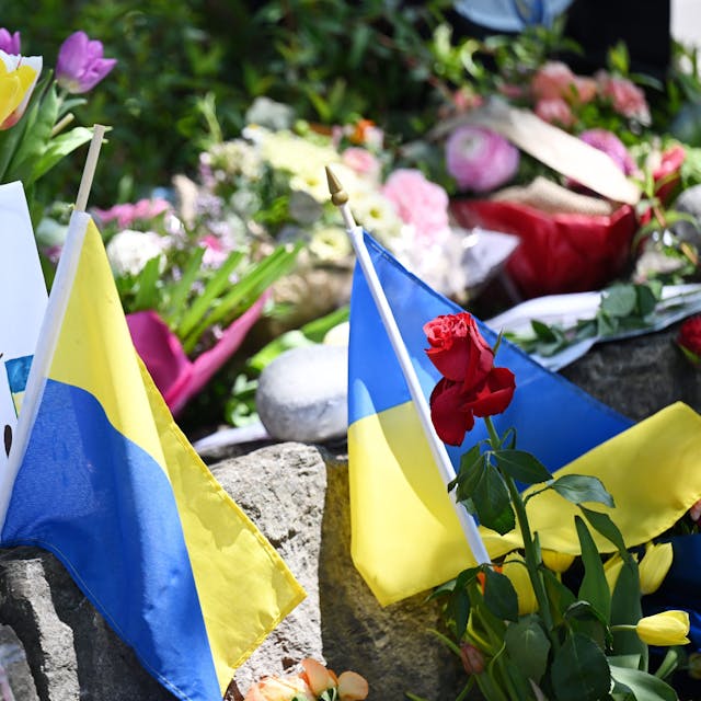 Neben dem Einkaufszentrum an dem am Samstagabend zwei Männer aus der Ukraine getötet worden sind, haben Menschen Blumen und Plakate niedergelegt. Die beiden getötete Ukrainer waren Armeeangehörige.
