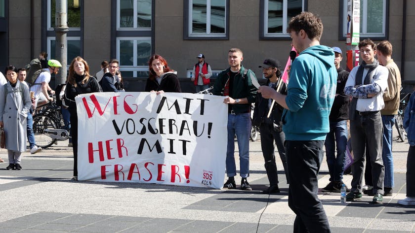 Studierende demonstrieren auf dem Albertus-Magnus-Platz. Auf einem Plakat steht: „Weg mit Vosgerau! Her mit Fraser!“
