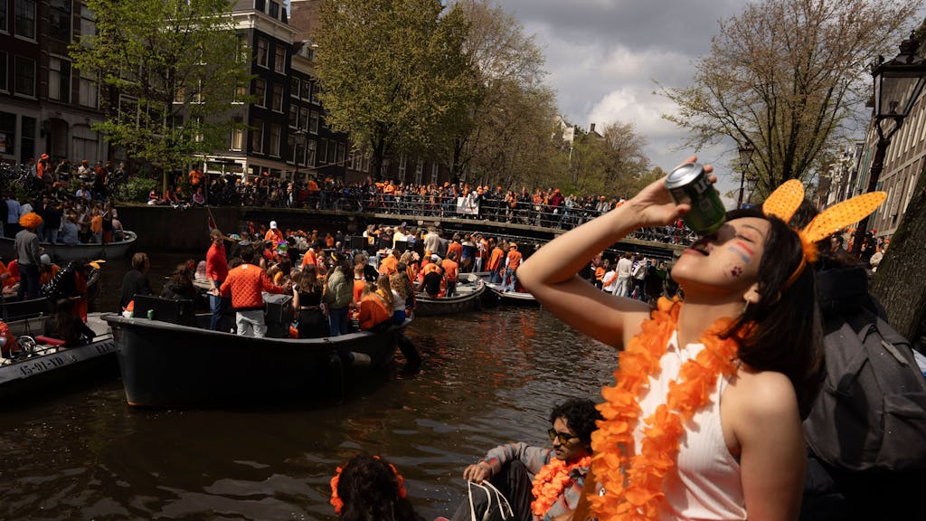 Menschen feiern den Königstag in den Grachten von Amsterdam.