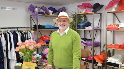 Norbert Hollender steht zwischen Regalen mit Hüten und Kleidung.&nbsp;