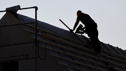 Ein Dachdecker arbeitet auf einem Einfamilienhaus (Symbolbild)