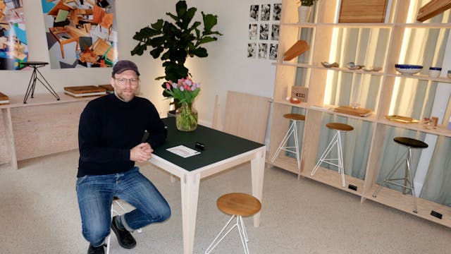 Gunnar Brand am Tisch „Joseph“ mit Hockern „Sisman“ in dem Ladenlokal der Möbel Compagnie.