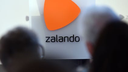 Das Logo des Onlineversandhändlers&nbsp;Zalando ist an einer Glasfassade zu sehen. Markant ist über dem Schriftzug ein orangefarbenes Dreieck zu erkennen.