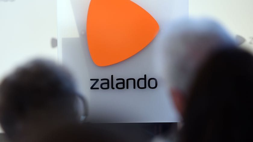 Das Logo des Onlineversandhändlers&nbsp;Zalando ist an einer Glasfassade zu sehen. Markant ist über dem Schriftzug ein orangefarbenes Dreieck zu erkennen.