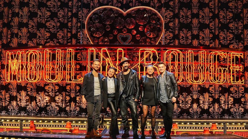 Fünf Personen stehen auf der Bühne vor einem Vorhang und dem Schriftzug "Moulin Rouge"