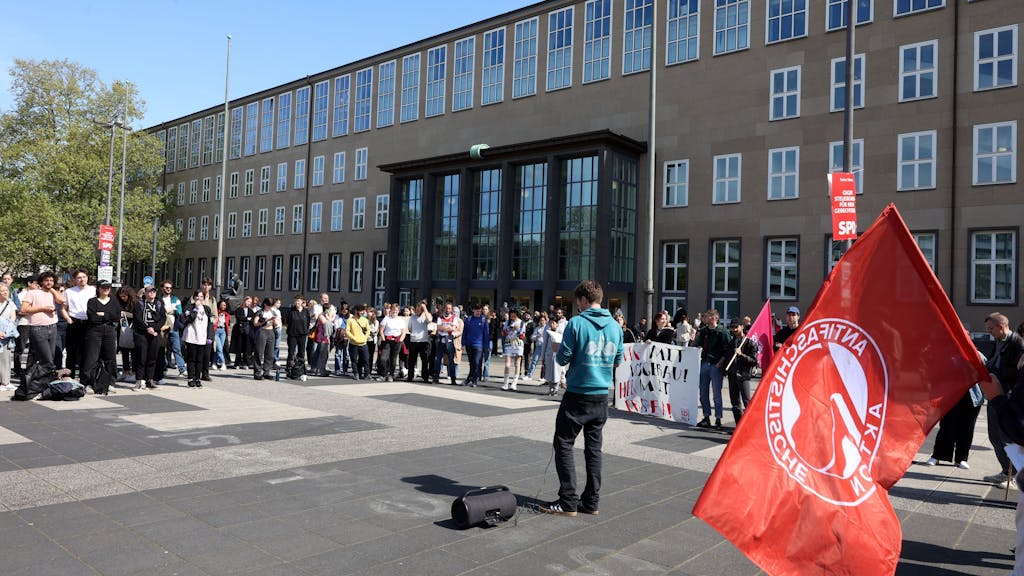 Viele junge Menschen stehen vor dem Haupteingang der Universität zu Köln und protestieren gegen Ulrich Vosgerau.