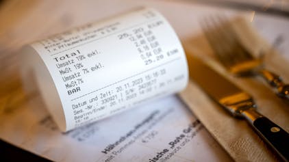 Eine Rechnung mit Umsatzsteuer und Mehrwertsteuer liegt auf der Speisekarte eines Restaurants.