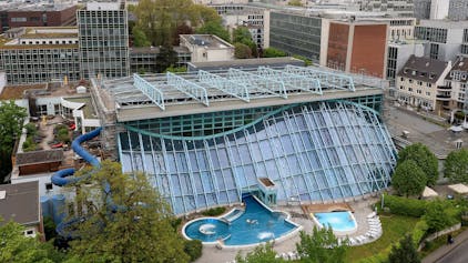 Blick aus der Luft auf das Agrippabad in Köln und die prägnante Glasfassade.