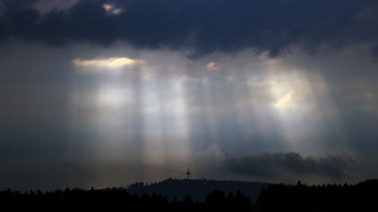 ARCHIV - 22.06.2021, Bayern, Rettenbach: Sonnenstrahlen dringen am Abend durch Wolkenlücken über dem Fernmeldeturm Weichberg. (zu dpa: «Erst Sonne, dann Gewitter: Unbeständiges Wetter zum Wochenende») Foto: Karl-Josef Hildenbrand/dpa +++ dpa-Bildfunk +++