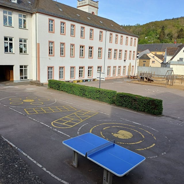 Das Bild zeigt den Blick auf die Grundschule mit dem Schulhof im Vordergrund.&nbsp;