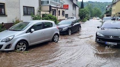 Autos fahren am 2. Mai im Schriesheimer Stadtteil Altenbach über eine überflutete Straße: Die Gemeinde Bisingen in Baden-Württemberg hat es besonders heftig getroffen.