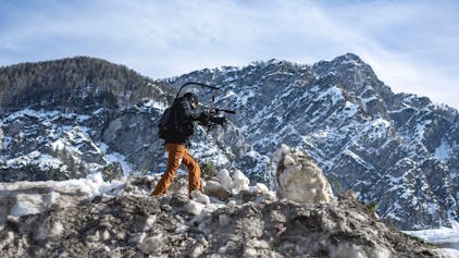 Eine Kamerafrau läuft über einen Haufen Schnee in den Bergen.