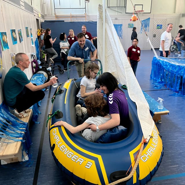 Kinder in einem Schlauchboot in einer Turnhalle