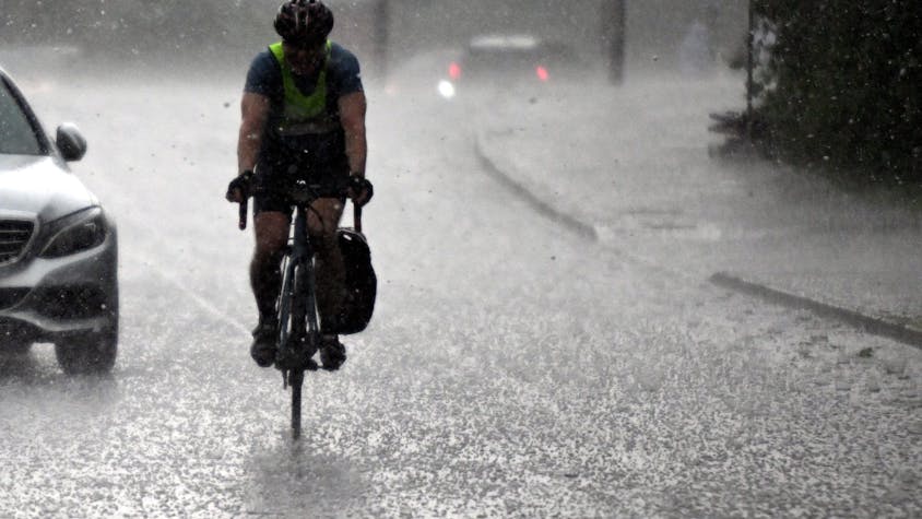 Ein Radfahrer fährt am 2. Mai durch einen Hagelschauer in Köln. Am Nachmittag sind erste schwere Gewitter mit kräftigem Regen durch Nordrhein-Westfalen gezogen.
