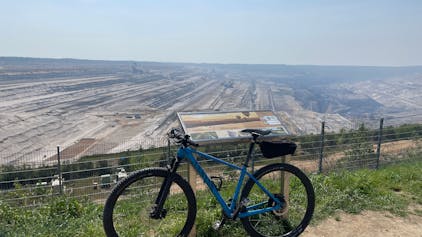 Ein Fahrrad steht vor der riesigen Hambacher Abbruchgrube.