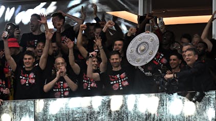 Leverkusens Spieler feiern den Gewinn der Deutschen Meisterschaft. Trainer Xabi Alonso hält eine Meisterschale in die Höhe.