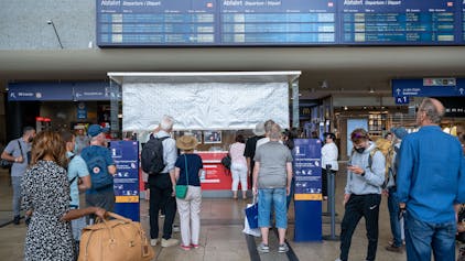 Reisende suchen nach Informationen auf den Anzeigetafeln im Hauptbahnhof.