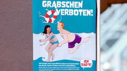 Eines von sechs Kampagnen-Plakaten gegen sexuelle Belästigung in Kölns Schwimmbädern zeigt einen Mann, der einem Mädchen unter Wasser an den Po greift, darüber steht in großen Buchstaben: „Stopp Grabschen verboten!“
