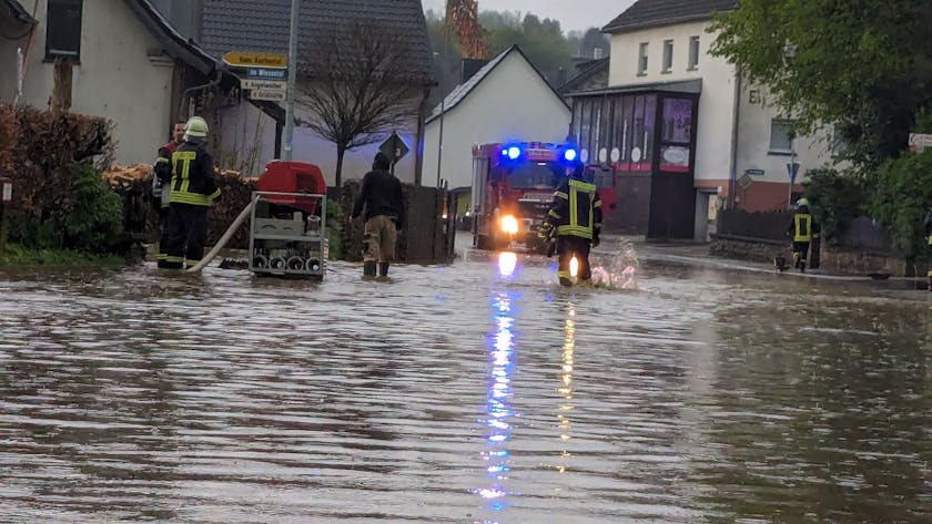 Das Bild zeigt eine überflutete Straße in Schmidtheim. Die Feuerwehr pumpt das Wasser ab.