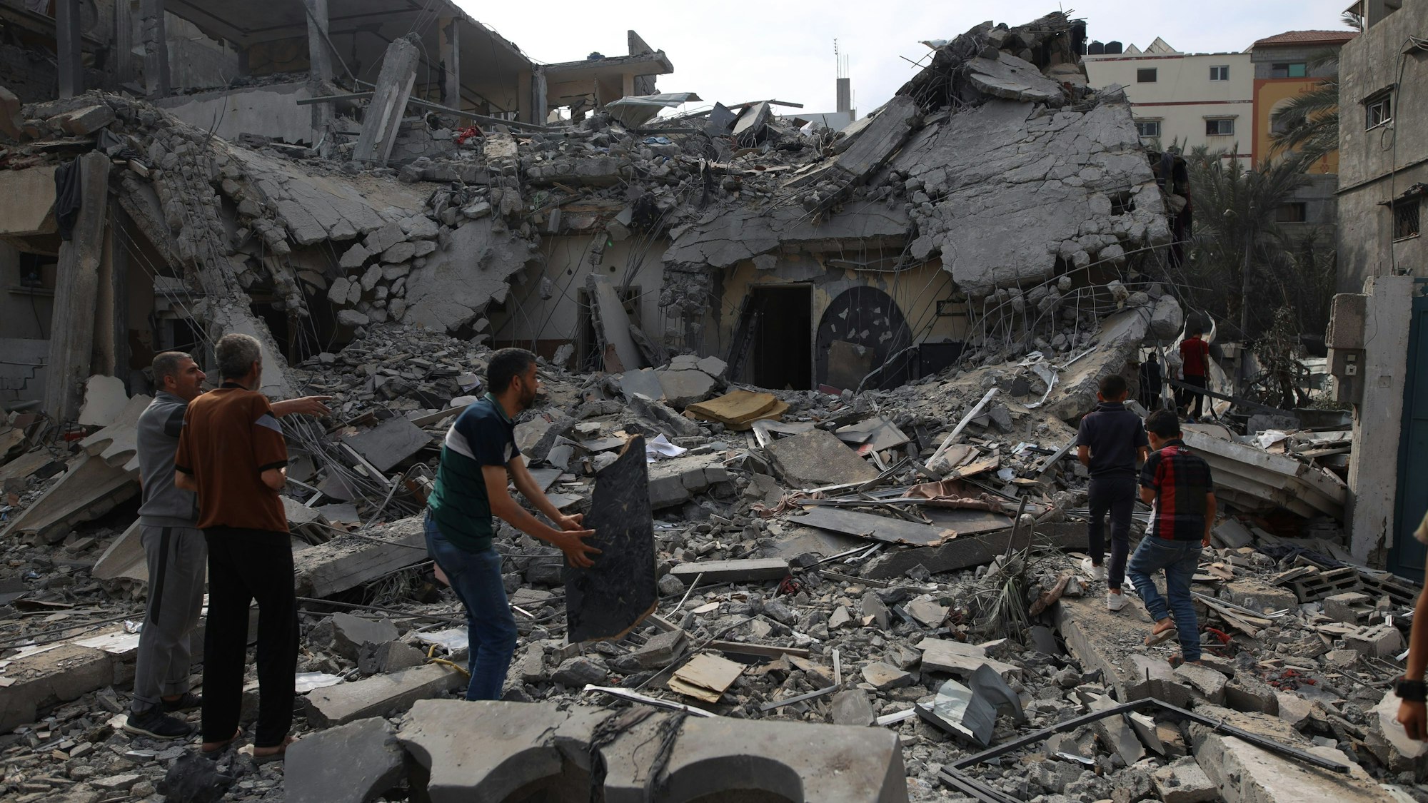 Menschen stehen inmitten der Trümmer eines zerstörten Hauses in der Stadt Deir el-Balah im Zentrum des Gazastreifens.