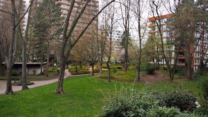 Blick auf den grünen Park mit hohen Bäumen, umgeben von den Wohnhochhäusern des Wohnpark Bayenthals. Foto von Stephanie Broch.