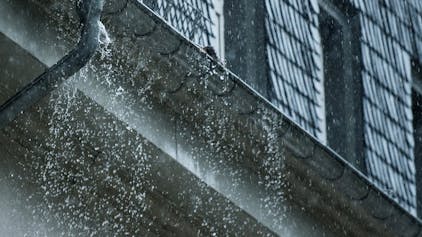 Viel Wasser fällt aus einer Regenrinne an einem Haus