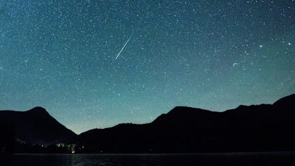 Bayern, Einsiedl: Eine Sternschnuppe leuchtet neben der Milchstraße am Himmel über dem Walchensee. (Archivbild)