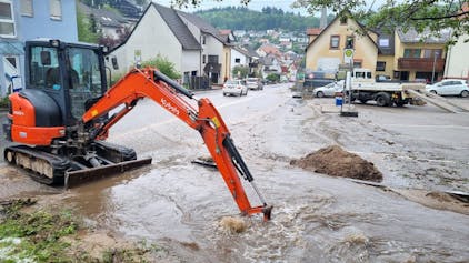 Ein Bagger versucht im baden-württembergischen Schriesheim einen übergelaufenen Bach freizuschaufeln. Schwere Unwetter haben in weiten Teilen Deutschlands Überflutungen, Hochwasser und teilweise sogar Katastrophenalarm ausgelöst.